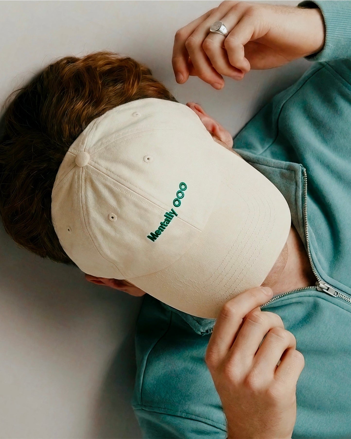 Person wearing a beige cap with green text 'Mentally OOO'