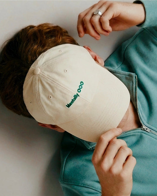 Person wearing a beige cap with green text 'Mentally OOO'